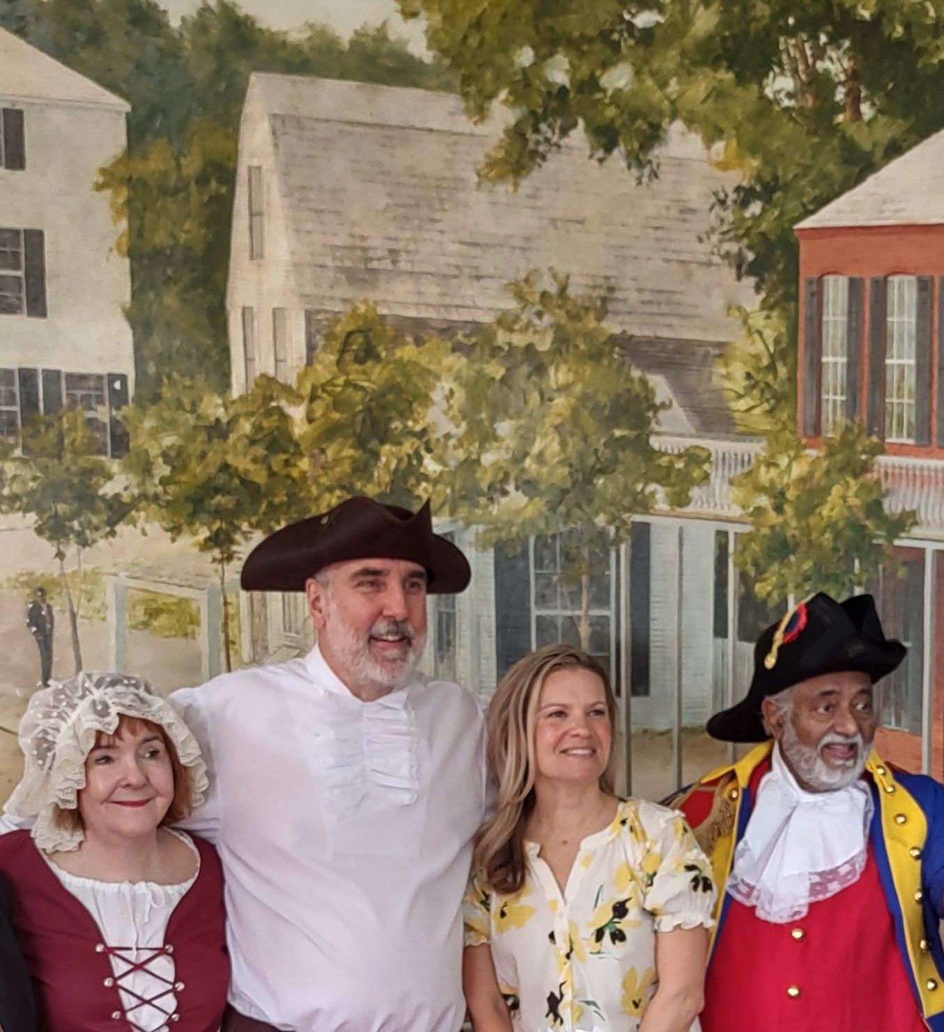 A group of people posing for a picture in front of a painting