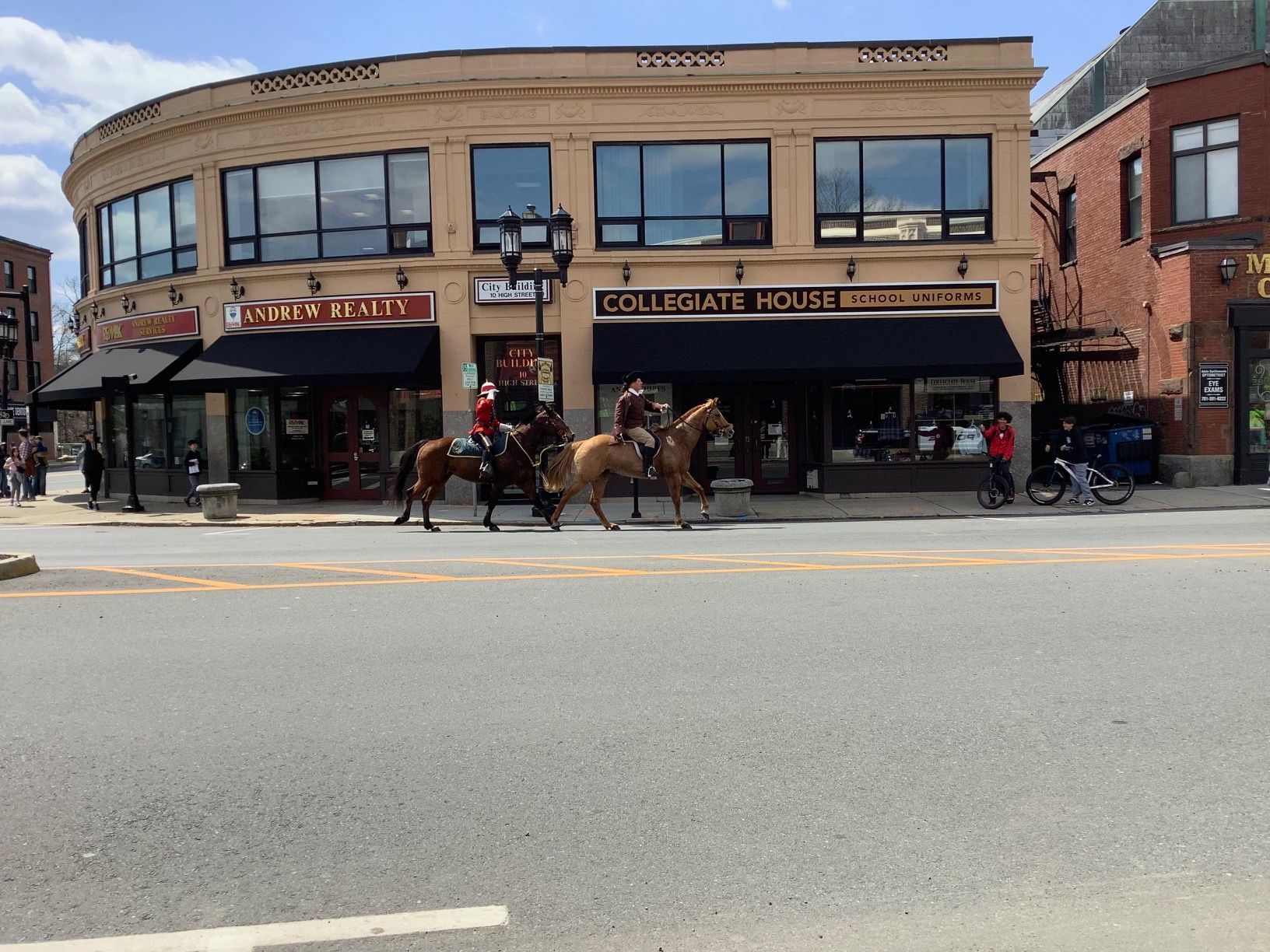 A group of people are riding horses down a street in front of a building that says collective health