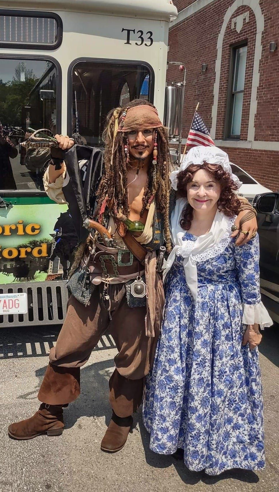 A man in a pirate costume is standing next to a woman in a dress.