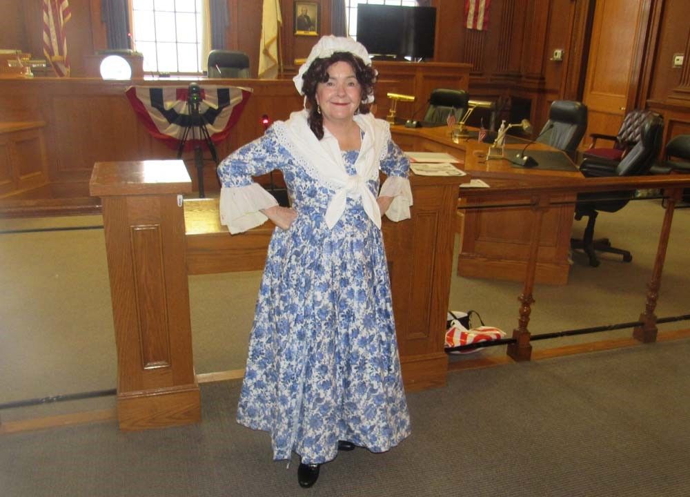 A woman in a blue dress is standing in a courtroom