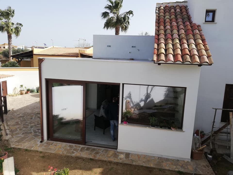 Una casa bianca con tetto di tegole e una porta scorrevole in vetro