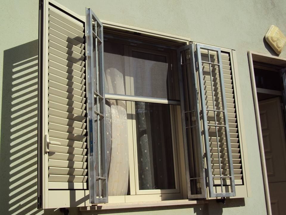 Una finestra con le persiane aperte su una parete verde