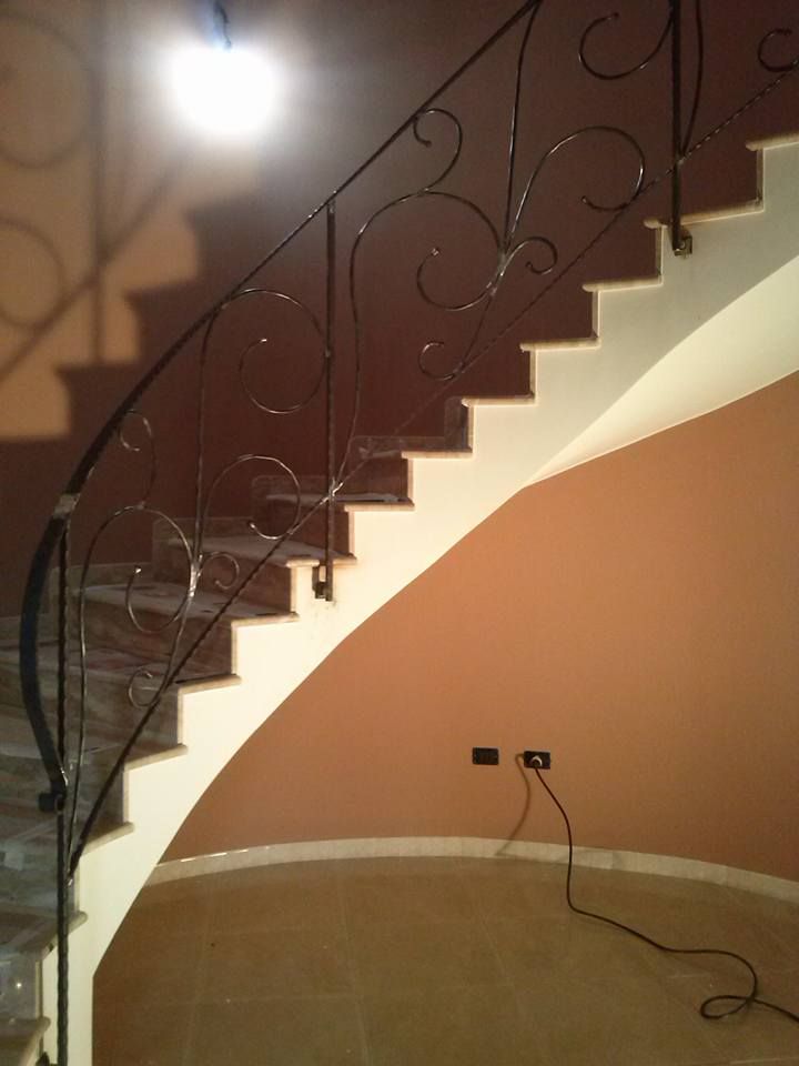 Una scala curva con ringhiera in ferro battuto
