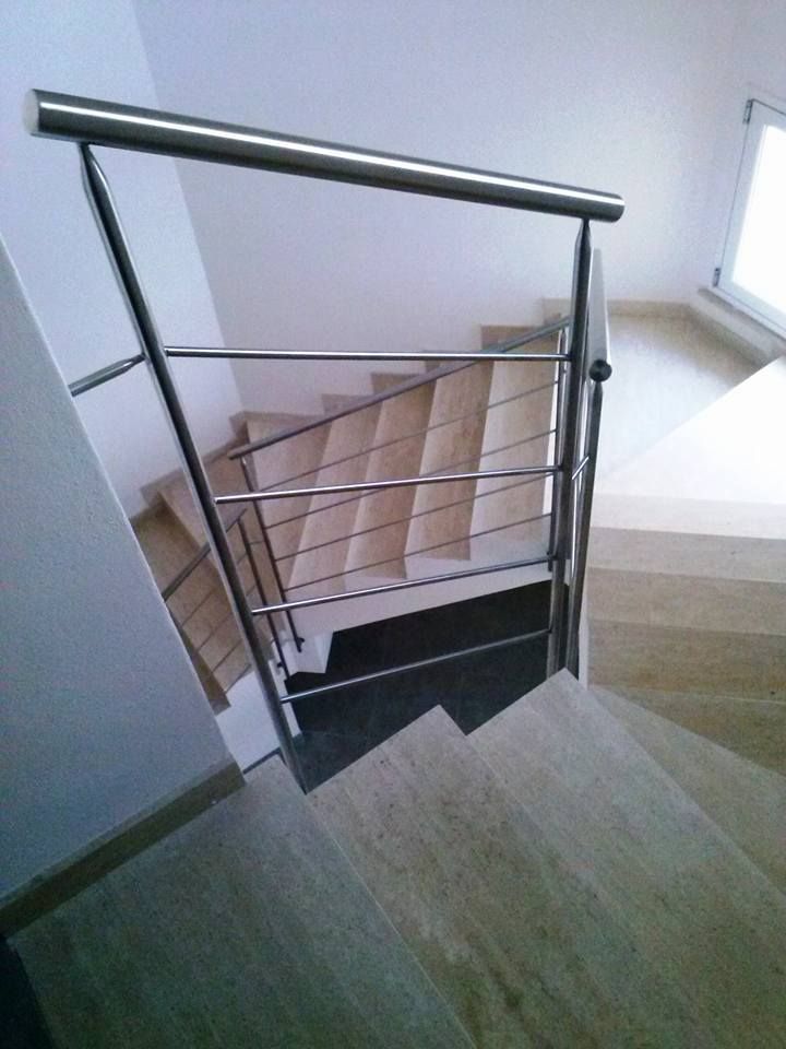 Una scala con ringhiera in acciaio inox e gradini in legno.