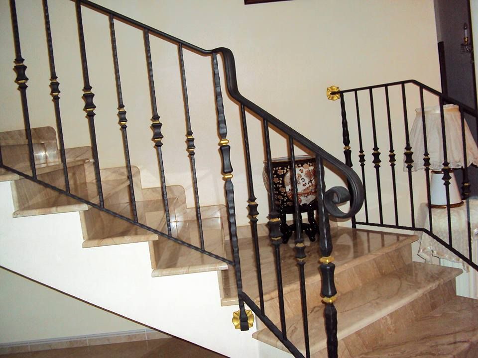 Una scala con ringhiera in ferro battuto e gradini in marmo