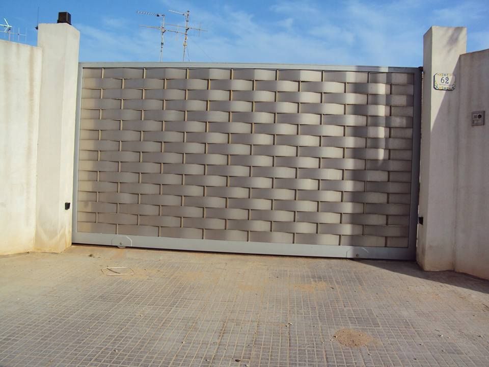 Un muro di mattoni con un cancello scorrevole di fronte