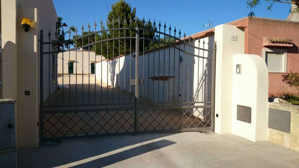 Un cancello in ferro battuto è aperto davanti a una casa