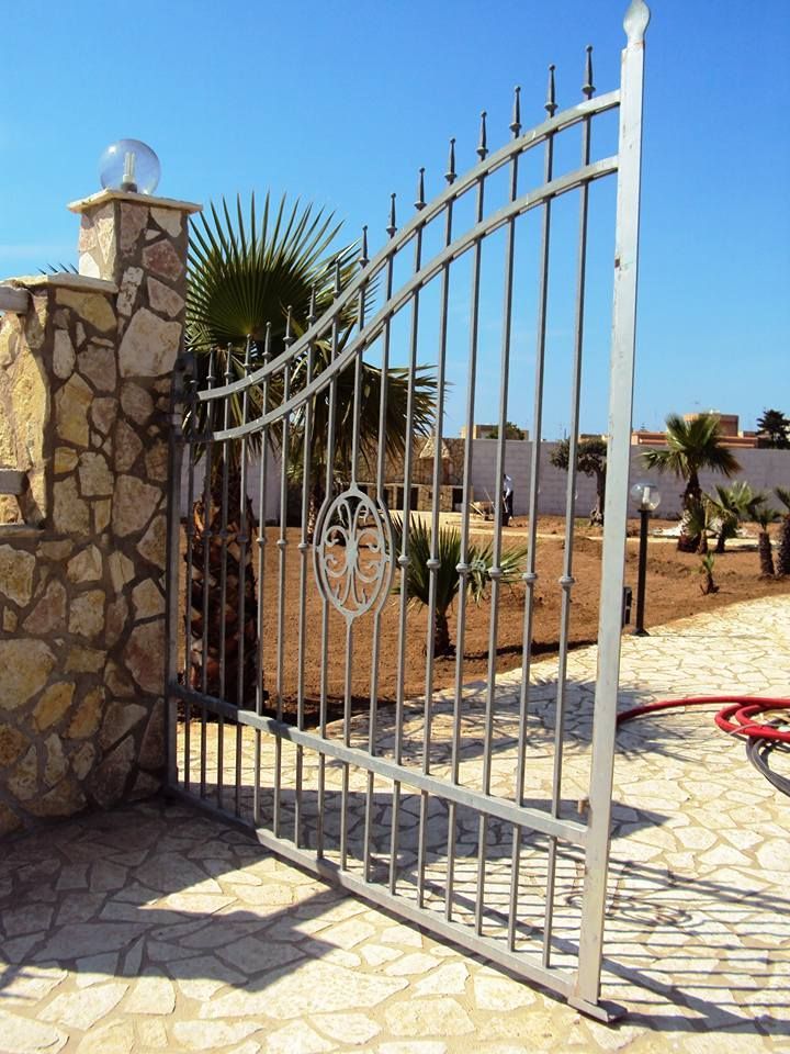 Un cancello in acciaio inossidabile è aperto su un muro di pietra