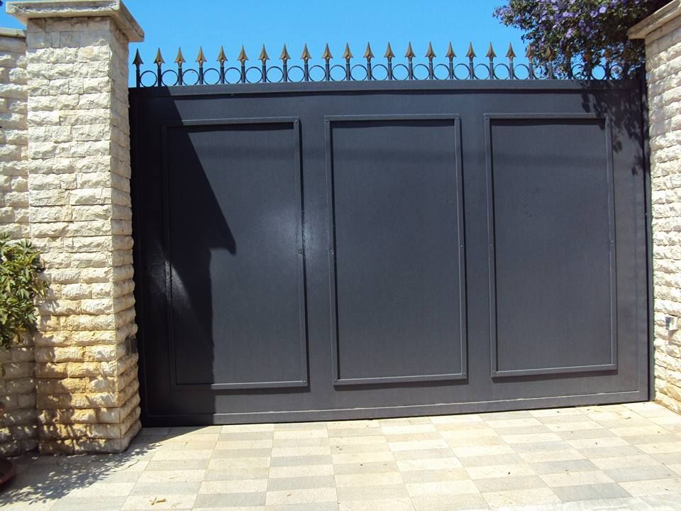 Un cancello nero con un muro di mattoni dietro