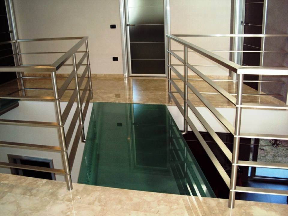Una scala con ringhiera in acciaio inox e pavimento in vetro