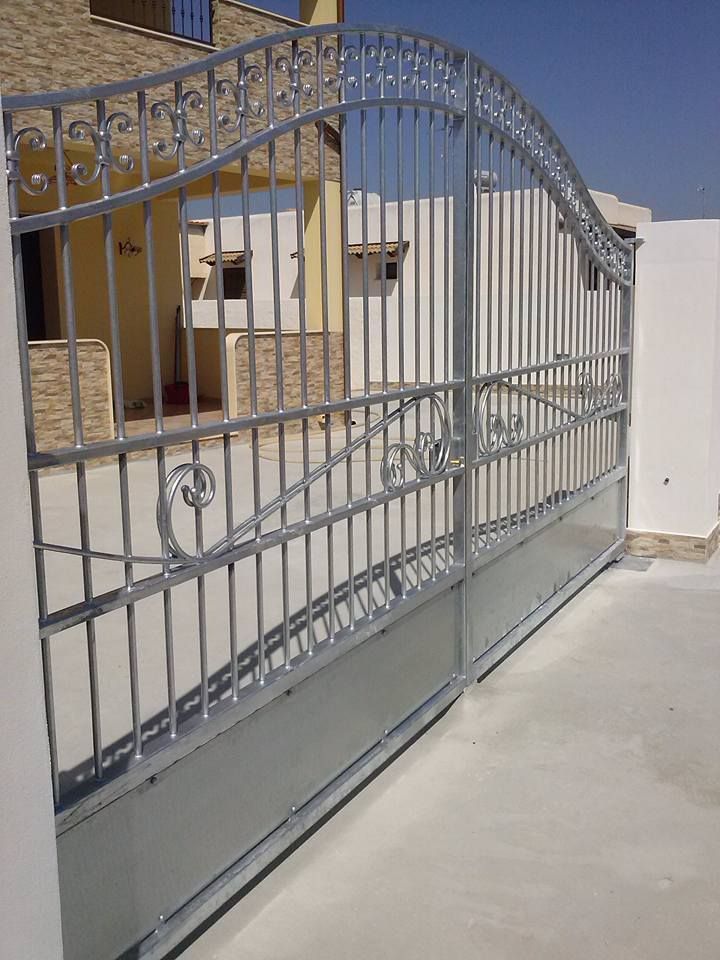 Un cancello in ferro battuto si trova davanti a una casa.