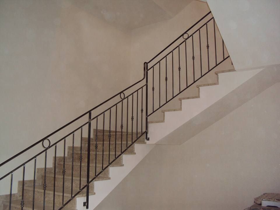 Una scala con ringhiera metallica che sale al secondo piano