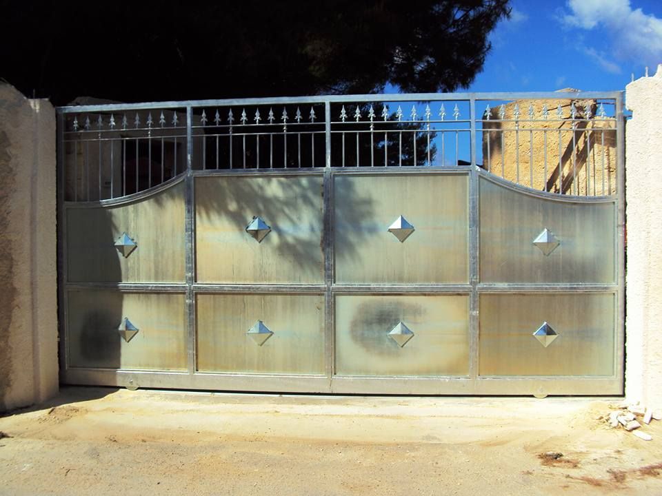 Una recinzione con un cancello scorrevole e un albero sullo sfondo