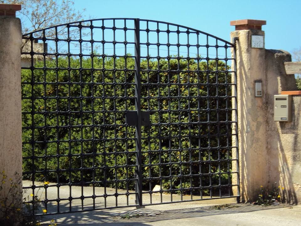 Un cancello in ferro battuto con una cassetta postale davanti