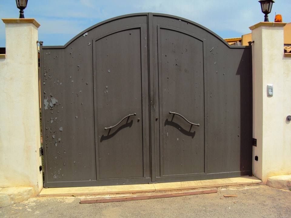 Un cancello nero con un muro bianco dietro