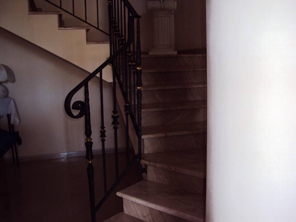 Una scala con ringhiera in ferro battuto e gradini in marmo