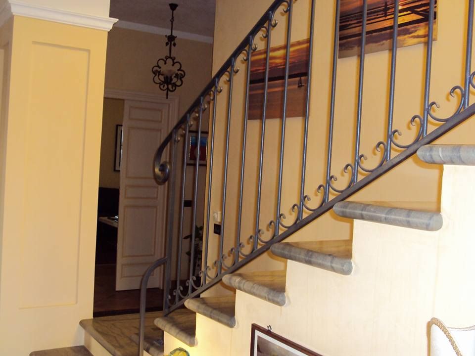 Una scala con ringhiera in ferro battuto e un quadro sul muro