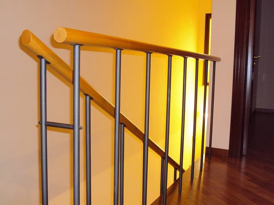 Una scala con ringhiera in metallo e corrimano in legno