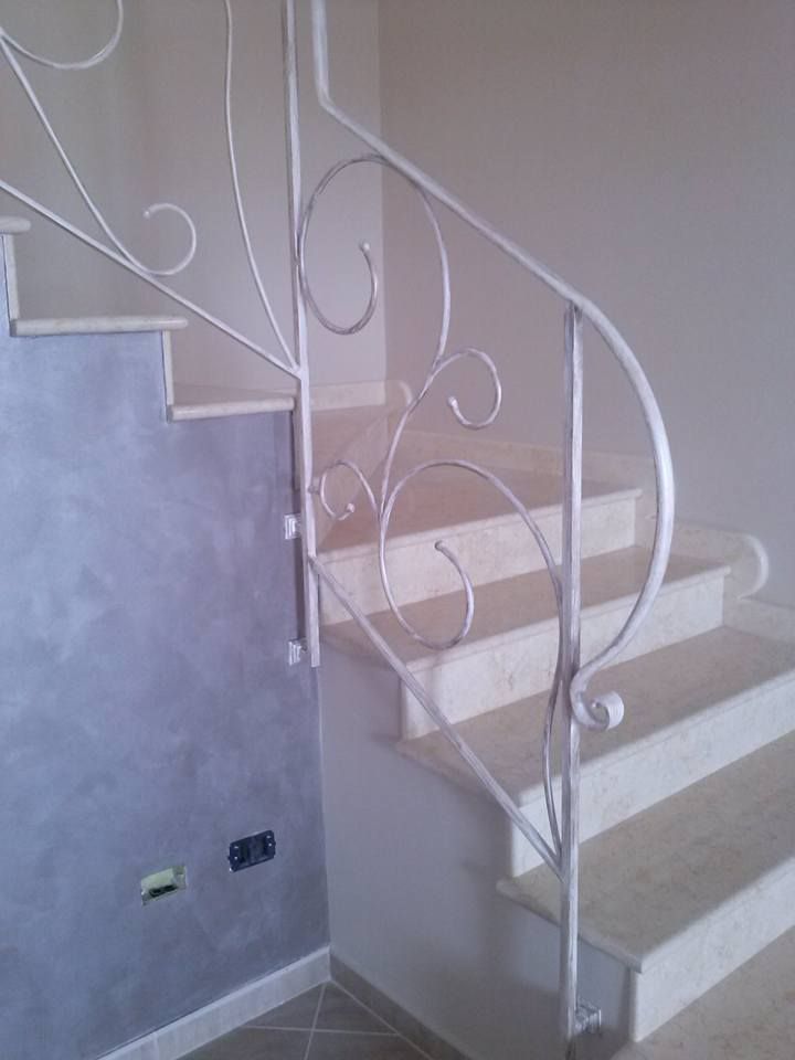 Una scala bianca con una ringhiera in ferro battuto in una stanza.