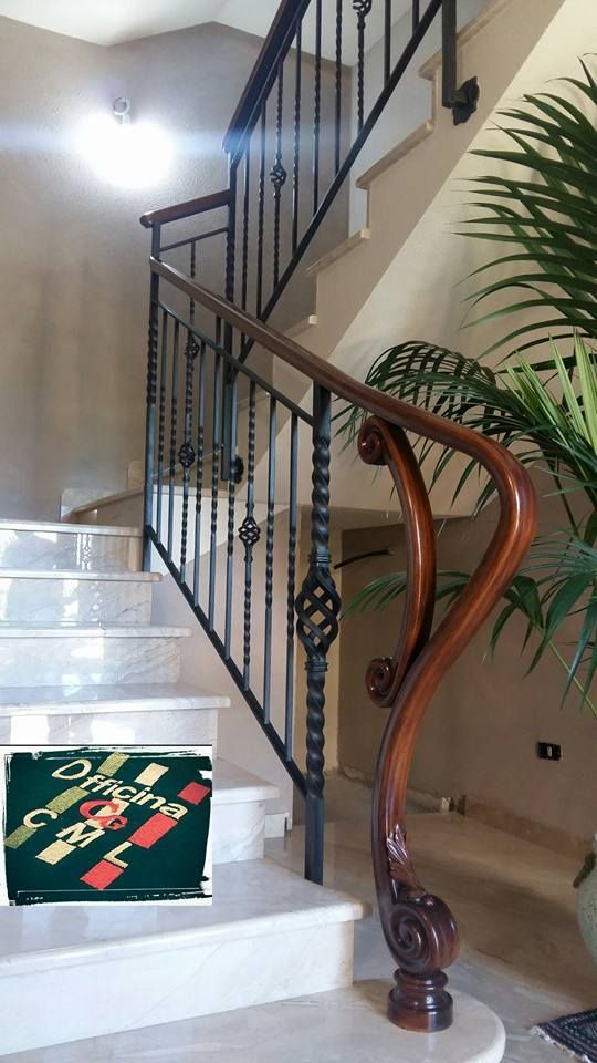 Una scala con ringhiera in ferro battuto e corrimano in legno
