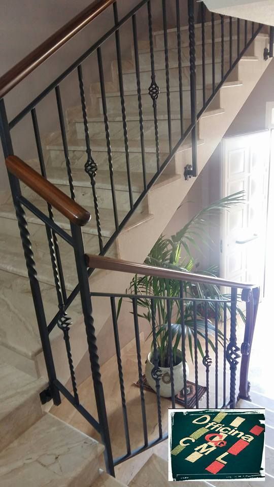 Una scala con ringhiera in ferro battuto e corrimano in legno
