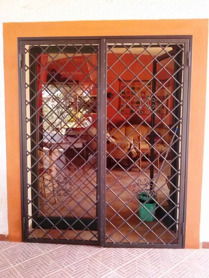 Una porta scorrevole in vetro con una griglia in ferro battuto