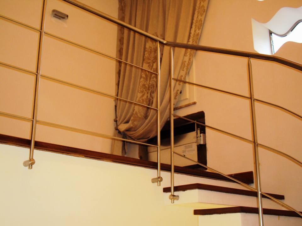 Una scala con ringhiera in acciaio inox e gradini in legno