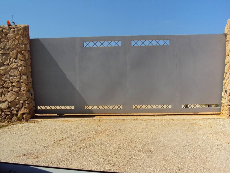 Un cancello scorrevole con un muro di pietra dietro