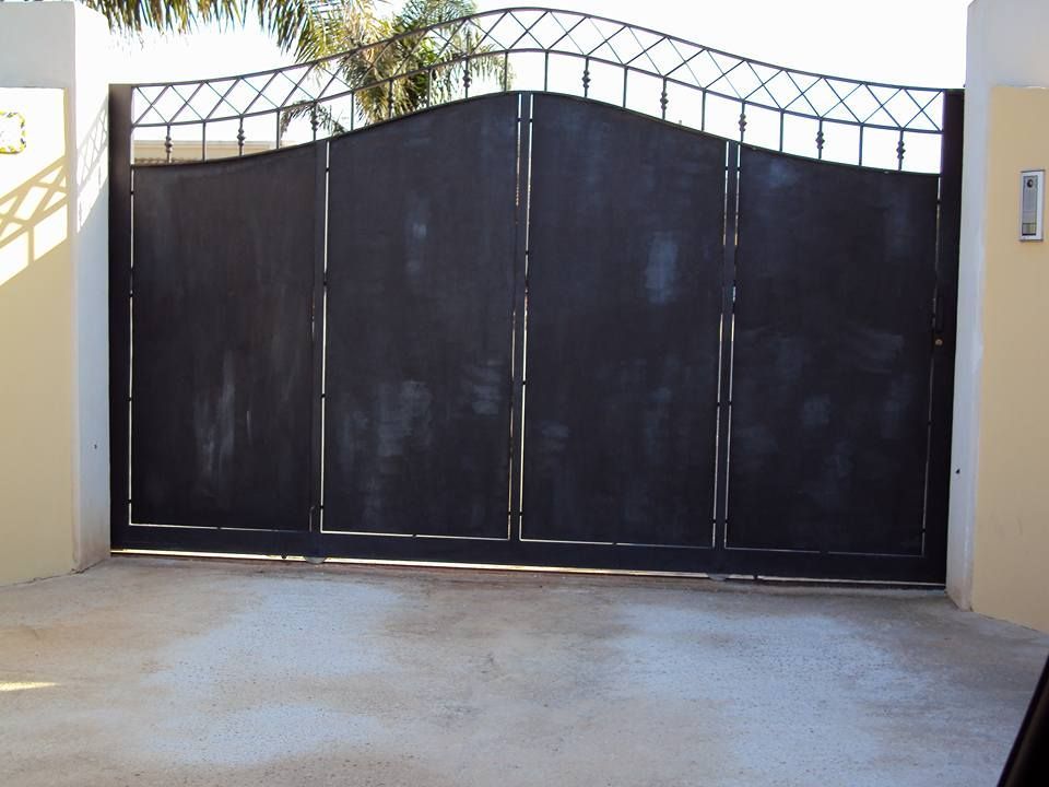 Un cancello nero con un muro giallo dietro