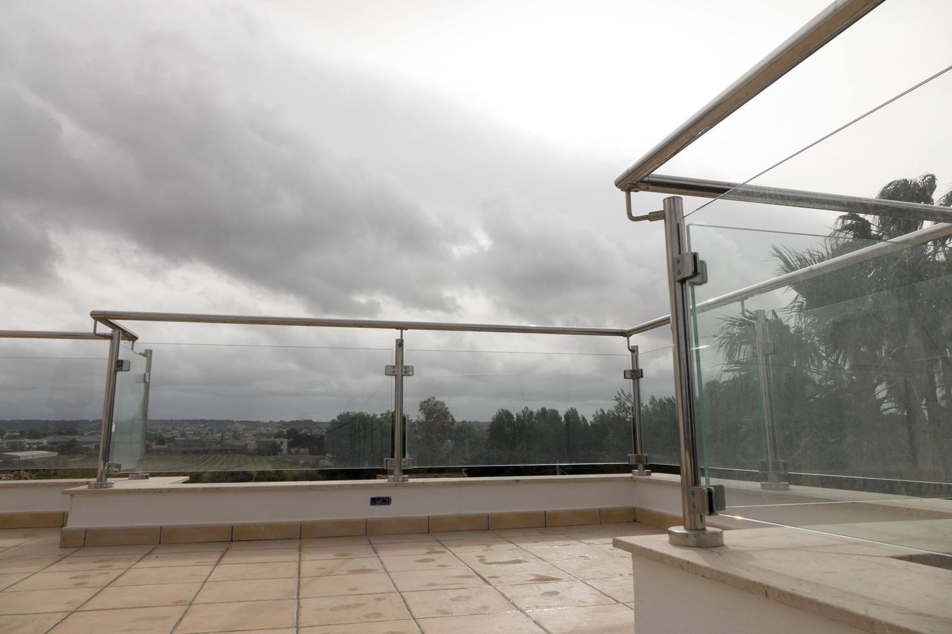 Un balcone con una ringhiera in vetro e un cielo nuvoloso sullo sfondo