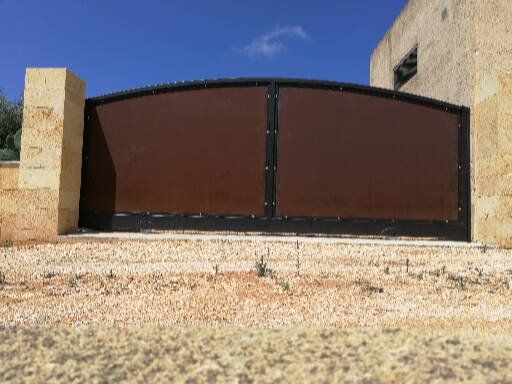 Un cancello marrone è posto di fronte a un muro di pietra.