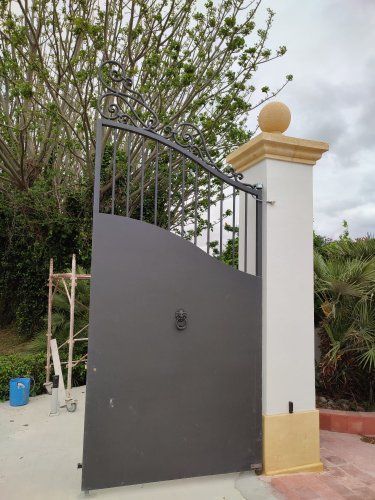 Un cancello nero è posto accanto a un pilastro bianco.