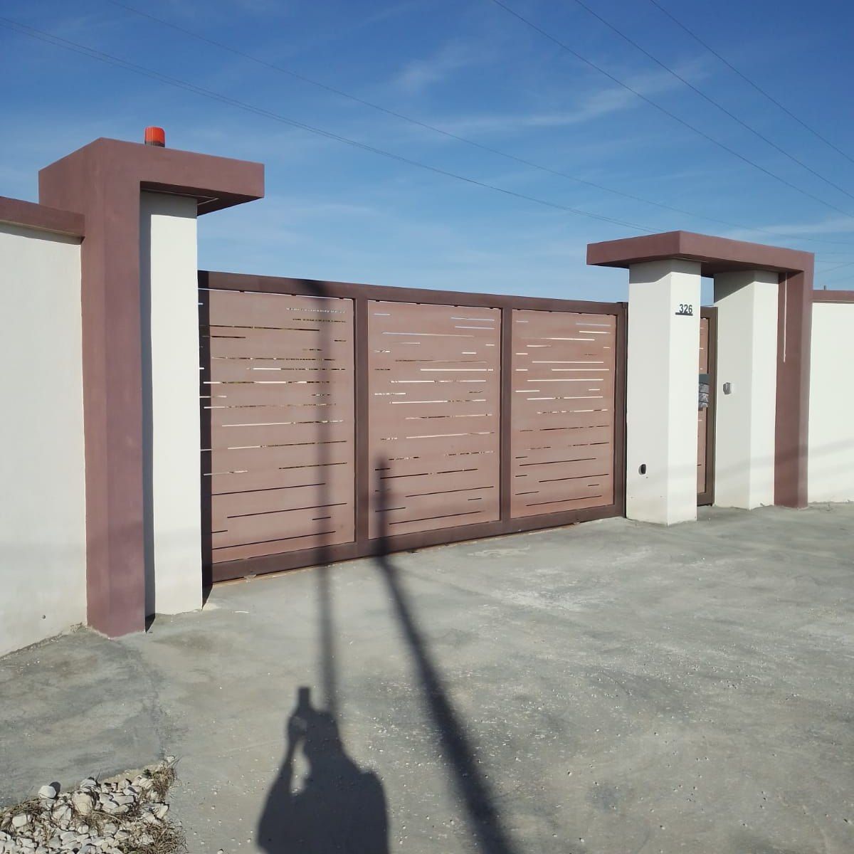 L'ombra di una persona è proiettata sul terreno davanti a una recinzione