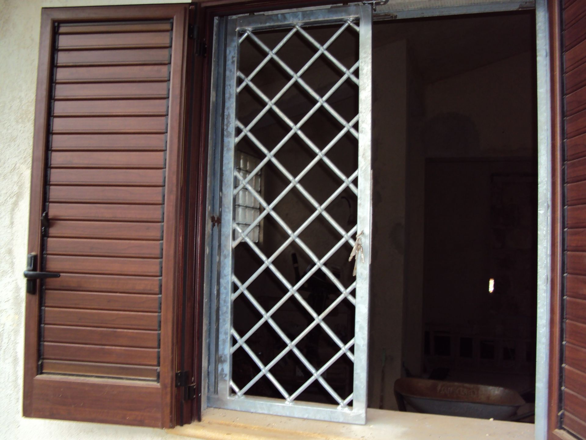 Una finestra con persiane di legno e un cancello di metallo