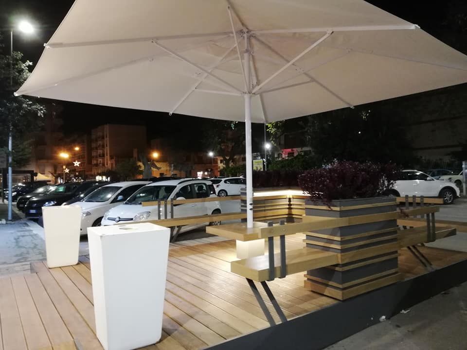 Un grande ombrellone bianco è appoggiato su un ponte di legno.