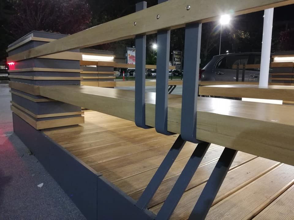 Una panchina di legno con una ringhiera di metallo in un parco di notte