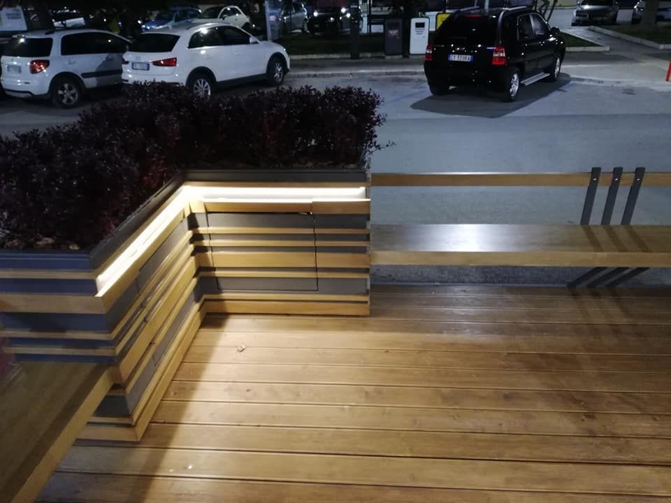 Un'auto è parcheggiata sul ciglio della strada accanto a una panchina di legno