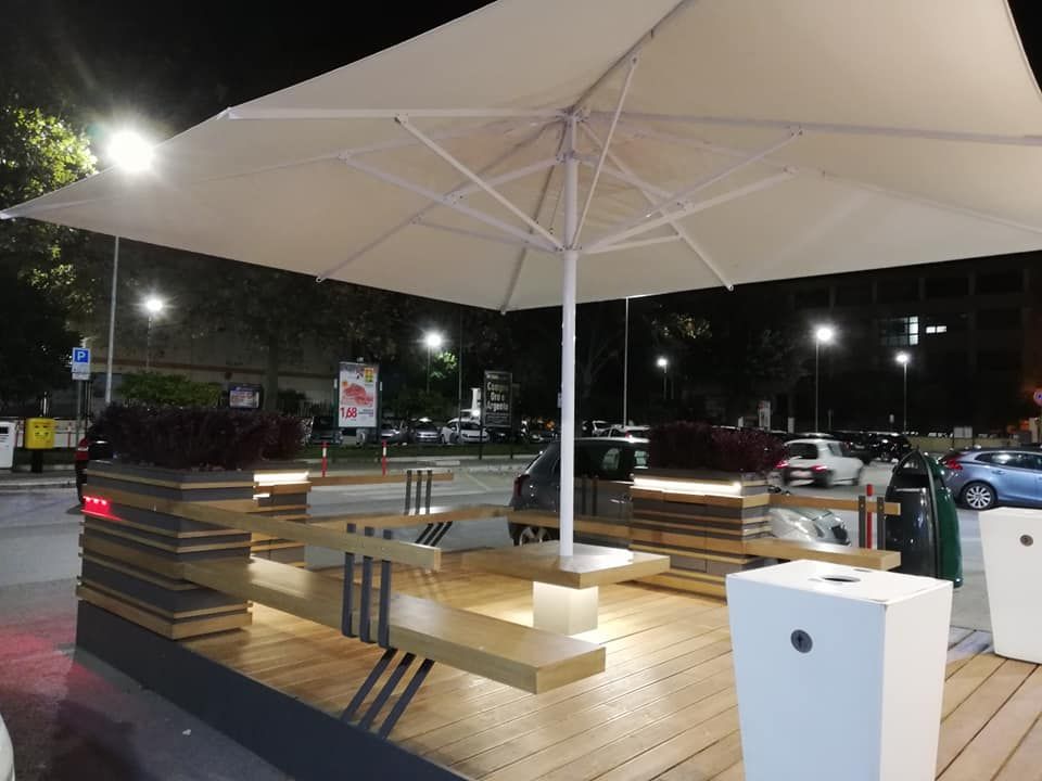 Un grande ombrellone bianco è appoggiato su un ponte di legno.