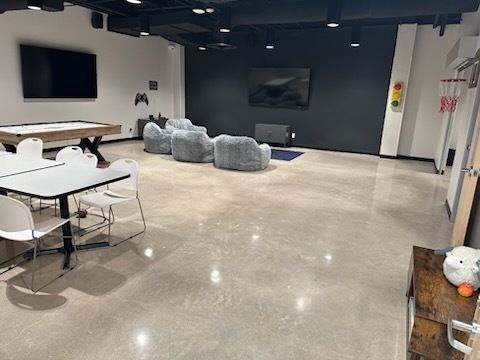 A large room with a pool table , chairs , tables and a television.