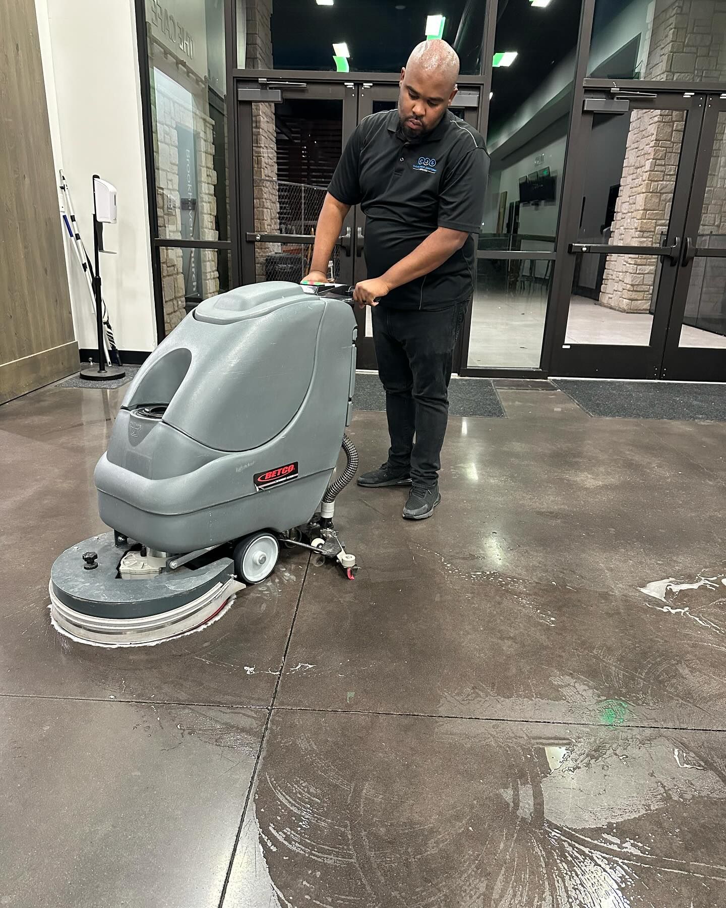 A man is cleaning a concrete floor with a machine.
