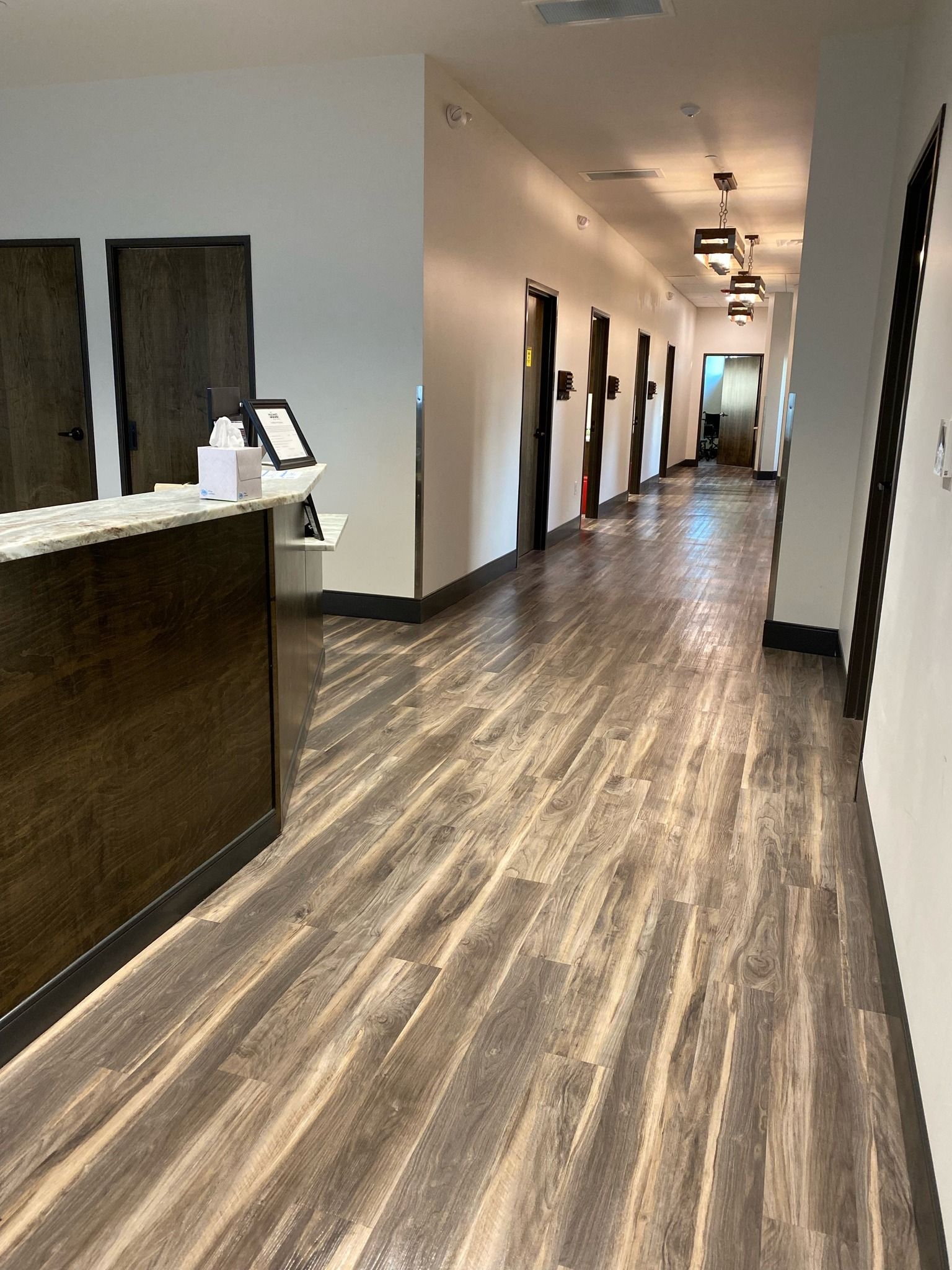 A long hallway with wooden floors and a reception desk in a hospital.