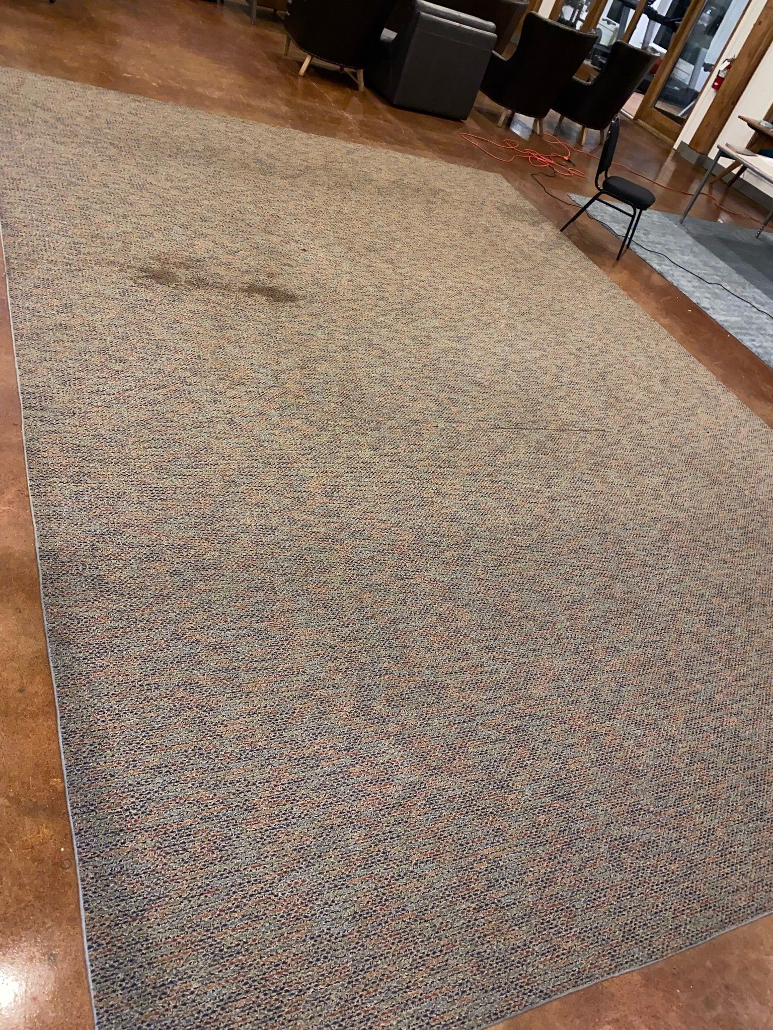 A large rug is sitting on a wooden floor in a living room.