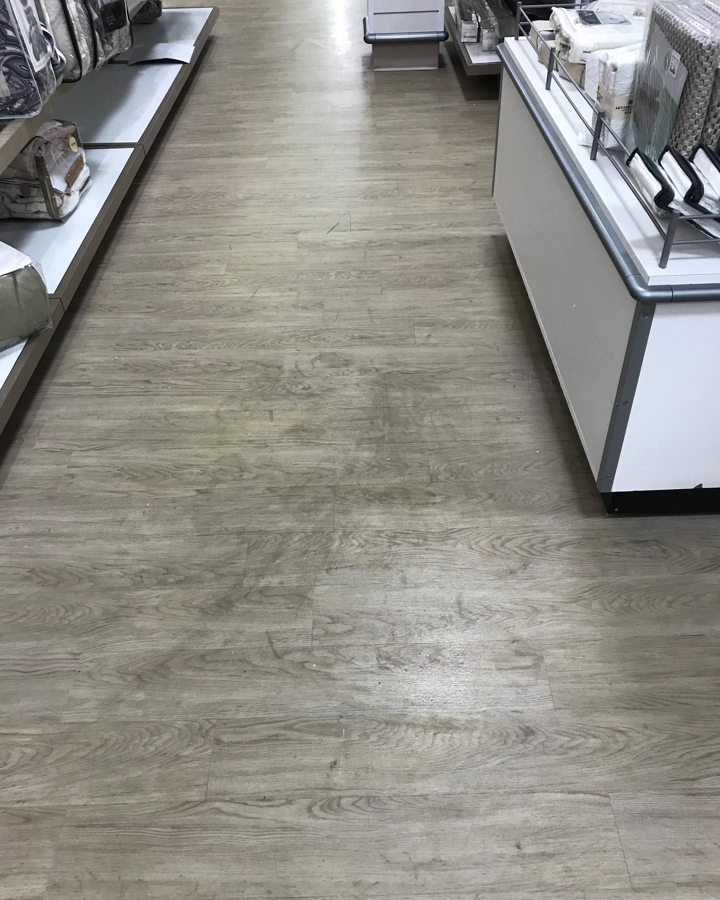 A wooden floor in a store with shelves and a counter.