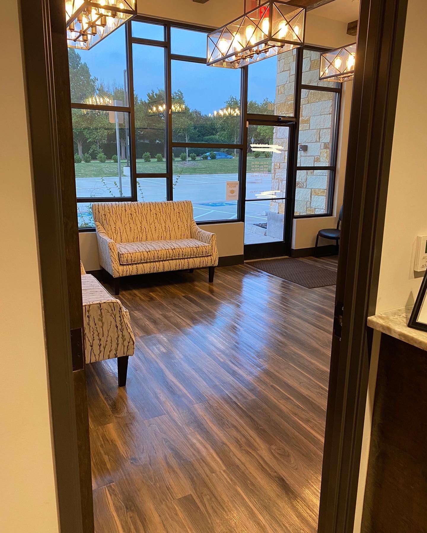 A waiting room with a couch and chairs and a large window.