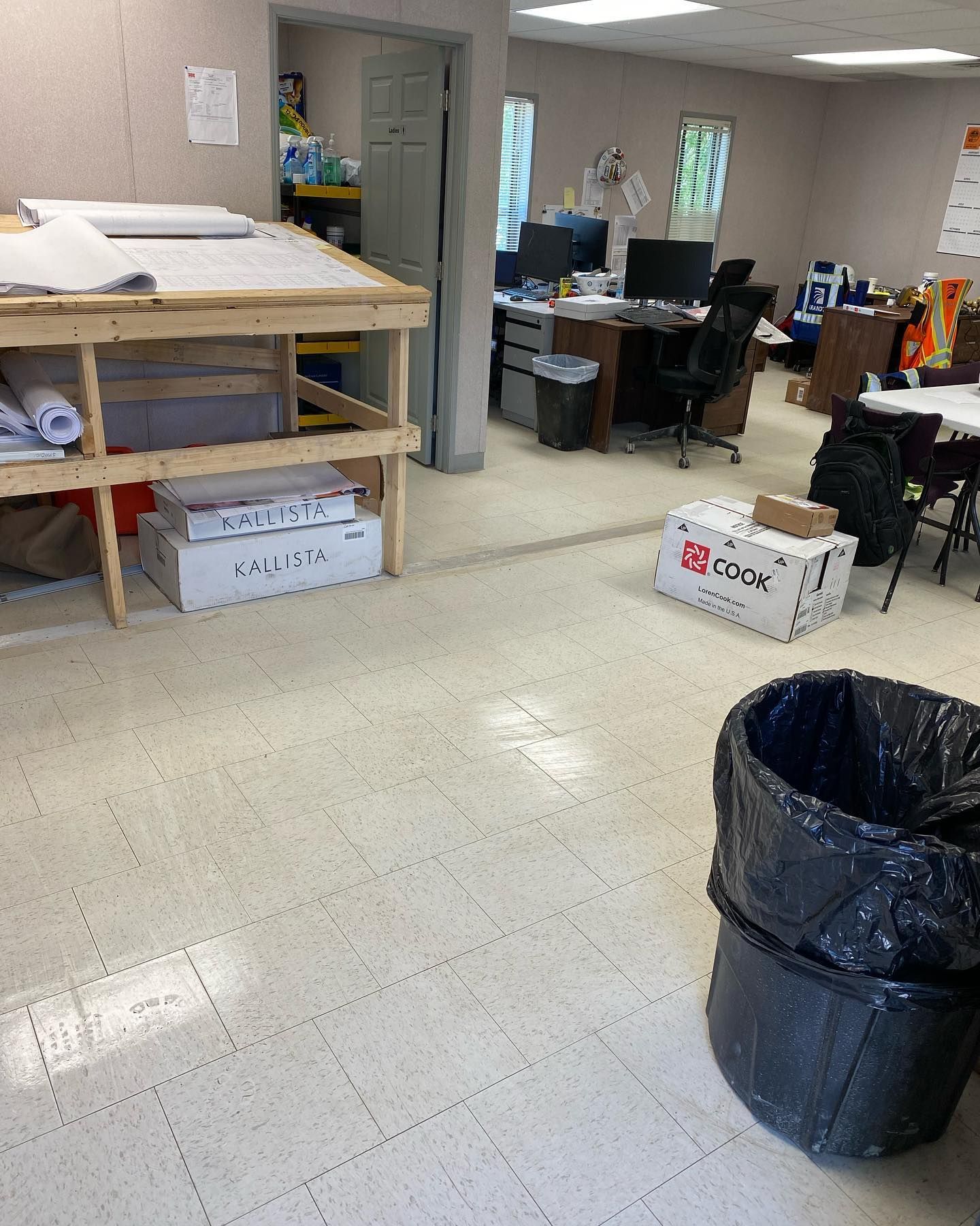 A room with boxes on the floor and a trash can
