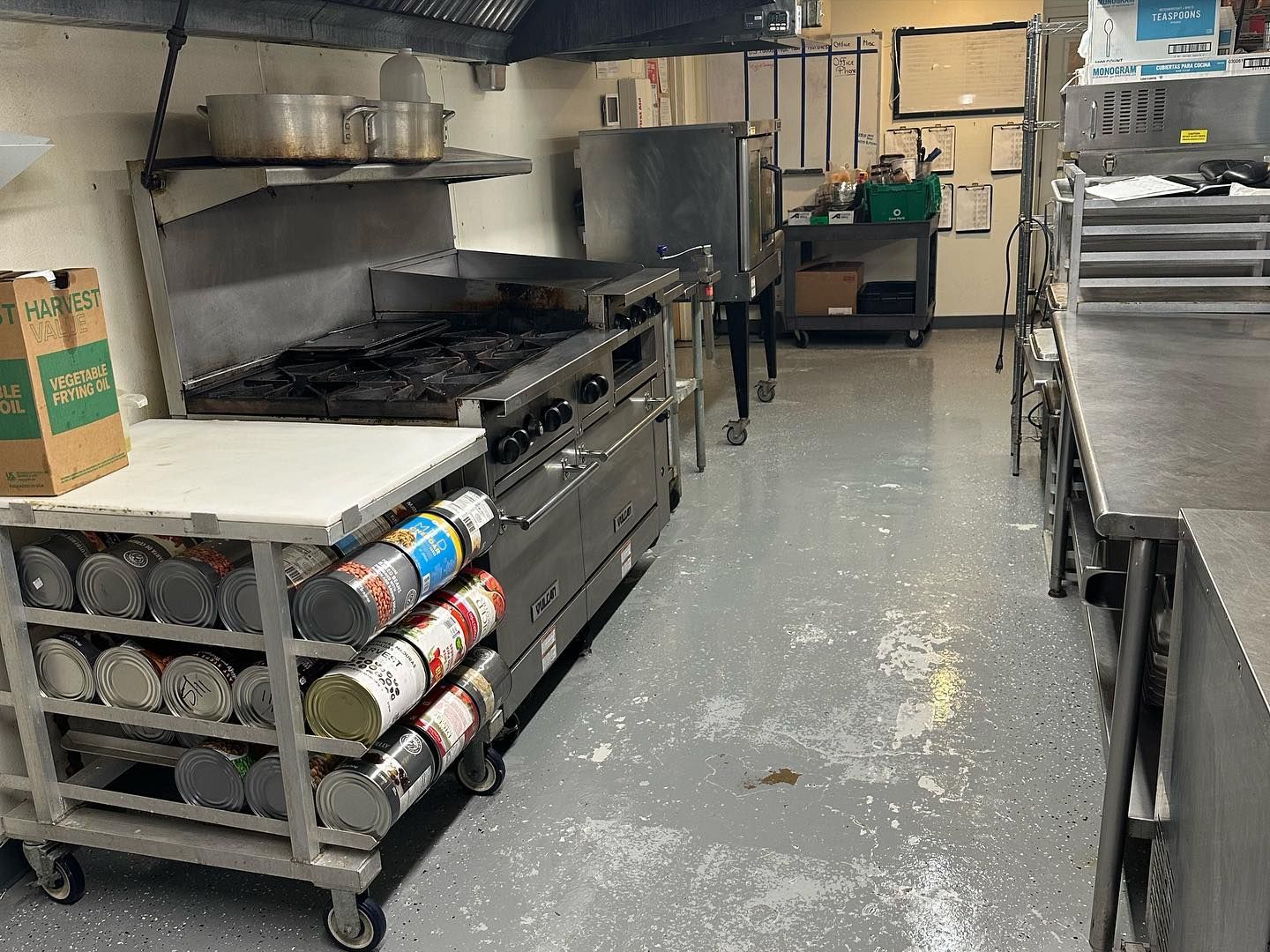 A kitchen with a stove and a bunch of cans on a cart.