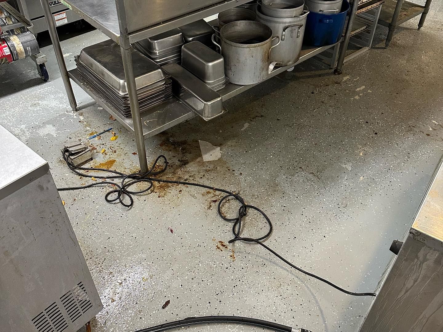 A dirty kitchen with a lot of pots and pans on the floor.