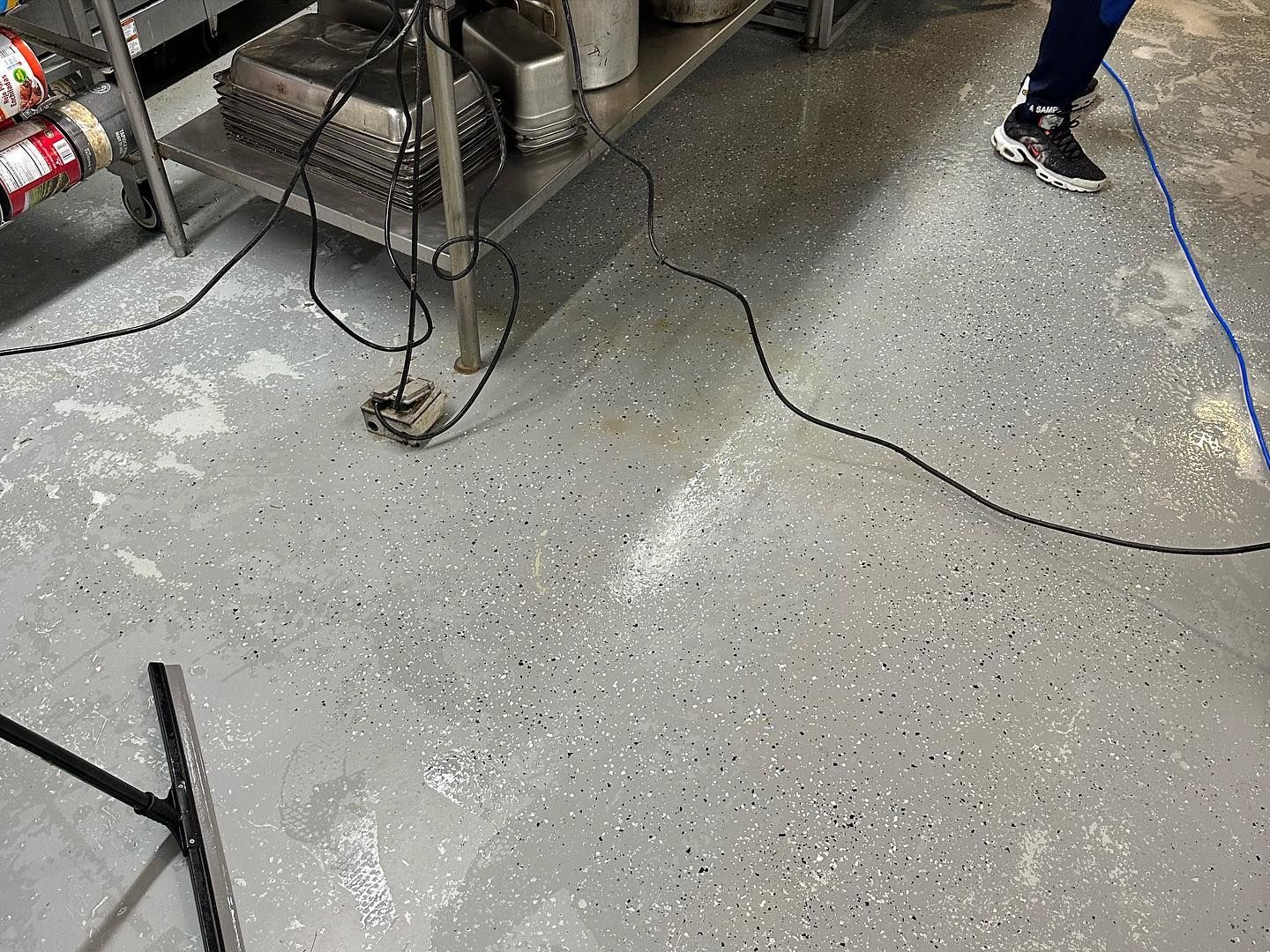 A person is cleaning a kitchen floor with a vacuum cleaner.