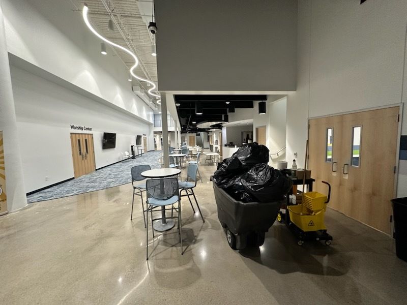 A large room with tables and chairs and a yellow mop.