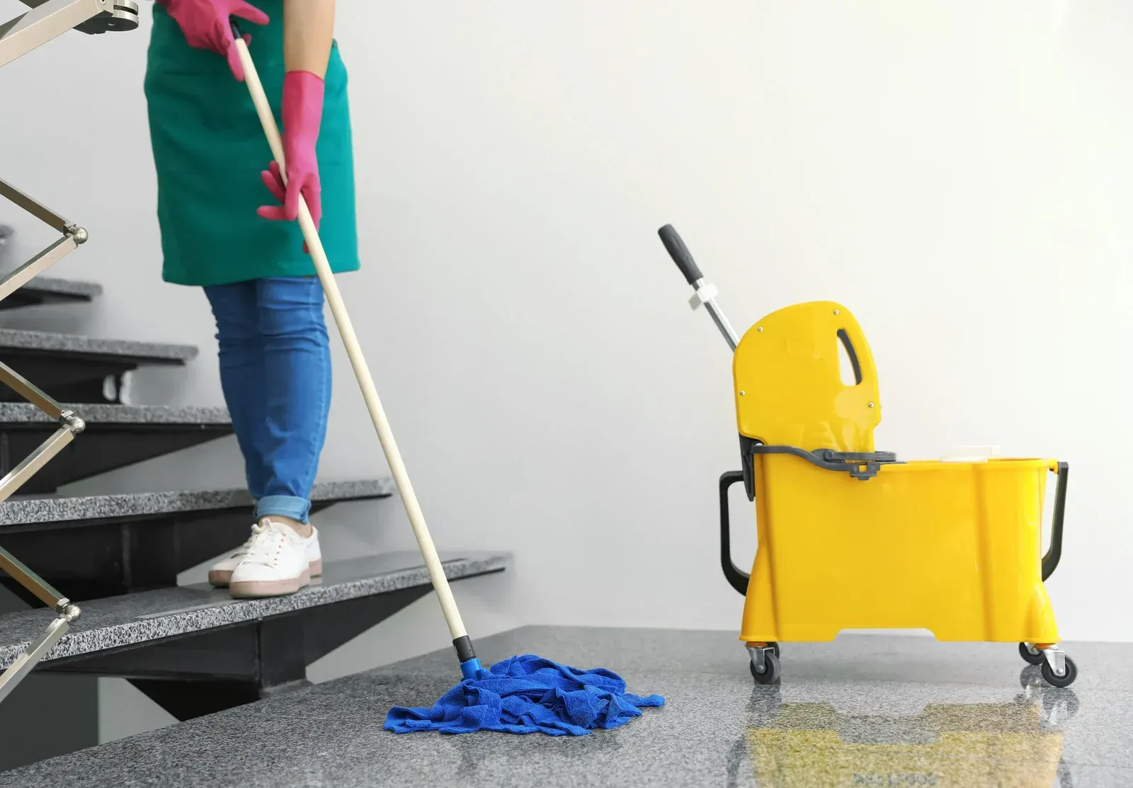 A woman is cleaning the stairs with a mop and bucket.